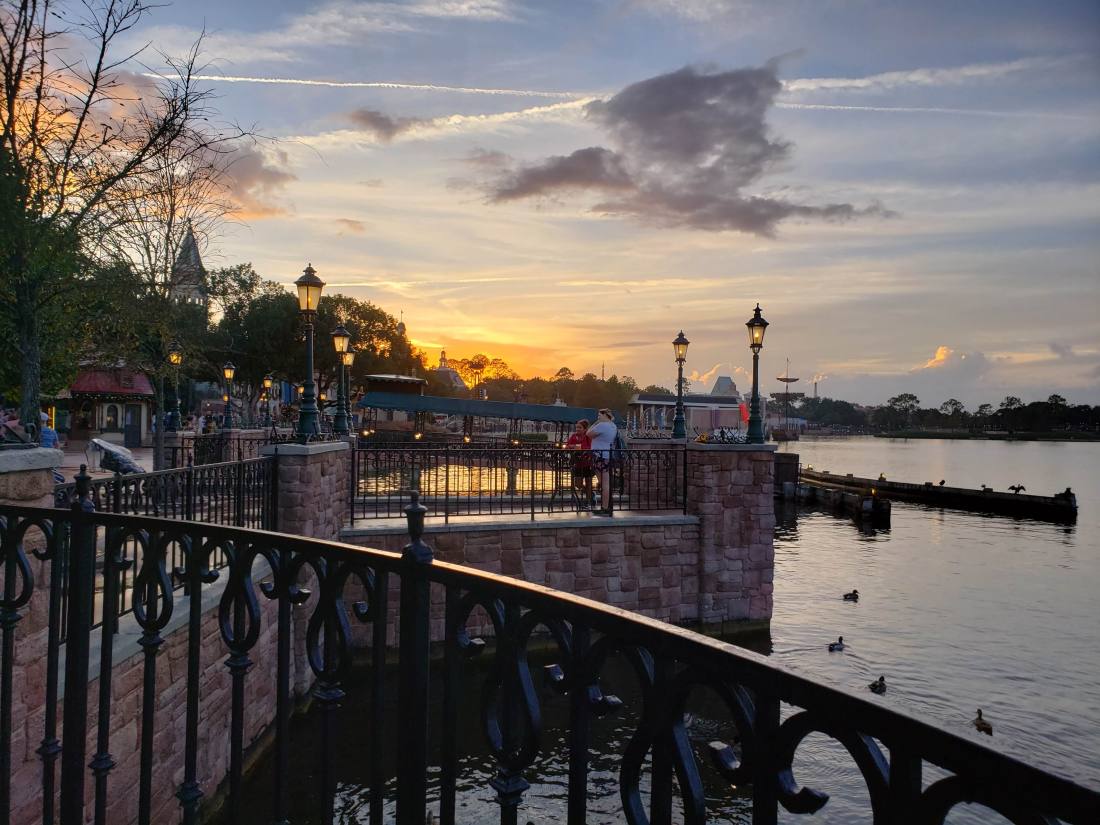 The sun is setting on a lake with a waterfront view.