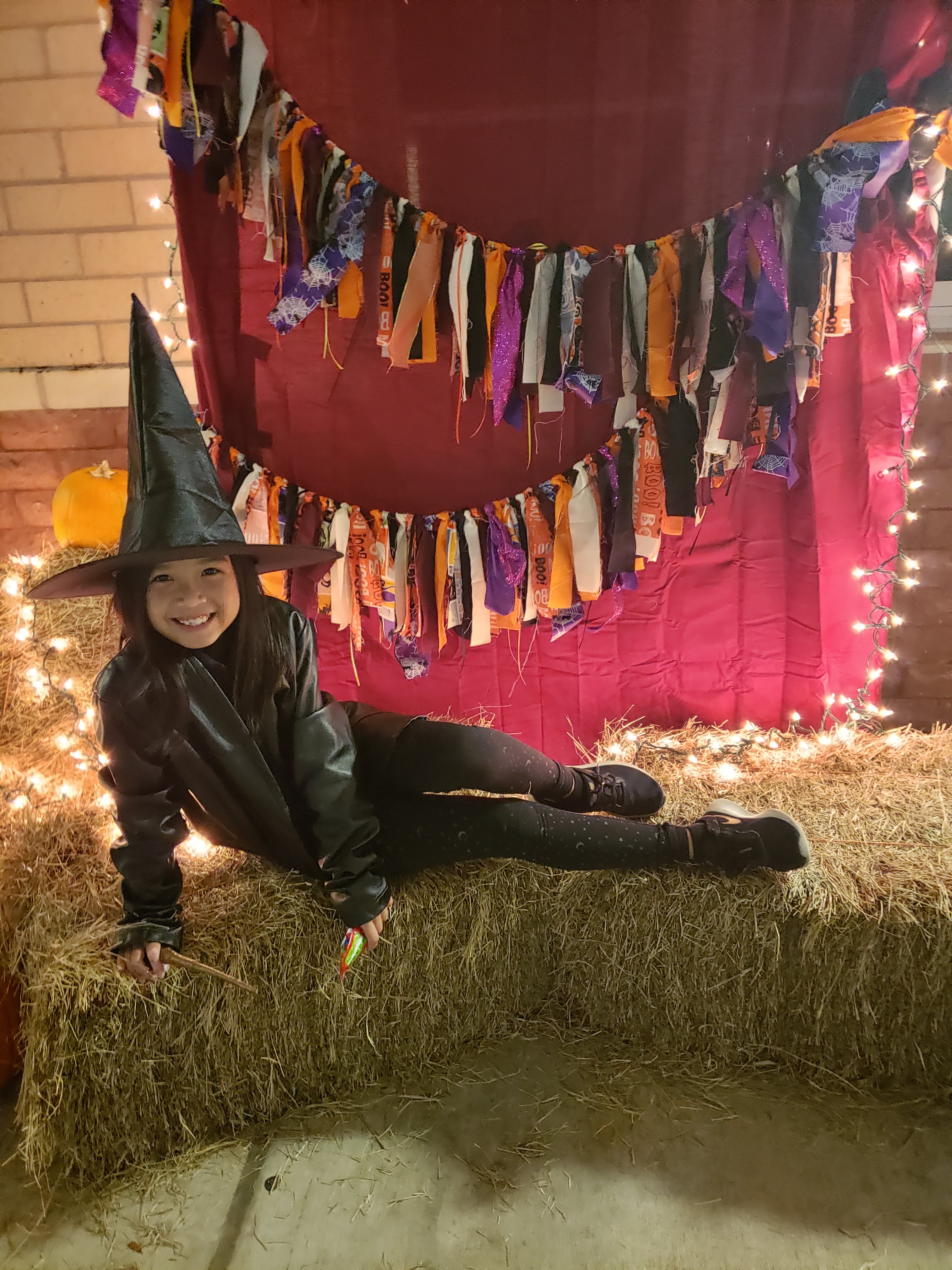 A photo of Kimmy from when she dressed up as a witch one year. She looks really happy on this bale of hay.